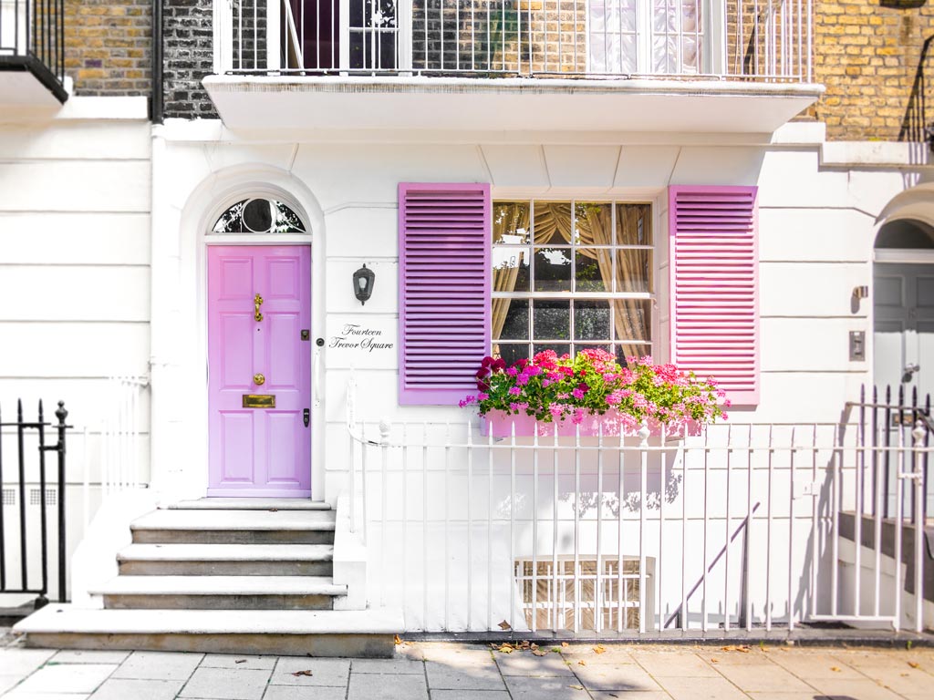 Facade of white house with purple door and shutters.