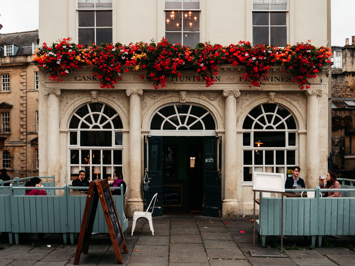 Fachada de piedra del pub Huntsman en Bath England, con flores rojas sobre la puerta