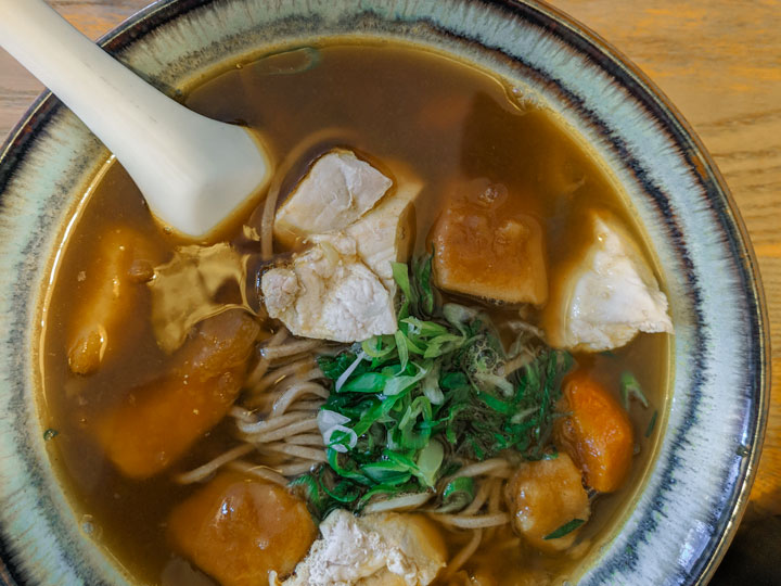 Bowl of soba in broth with chicken, carrot, and green onion.