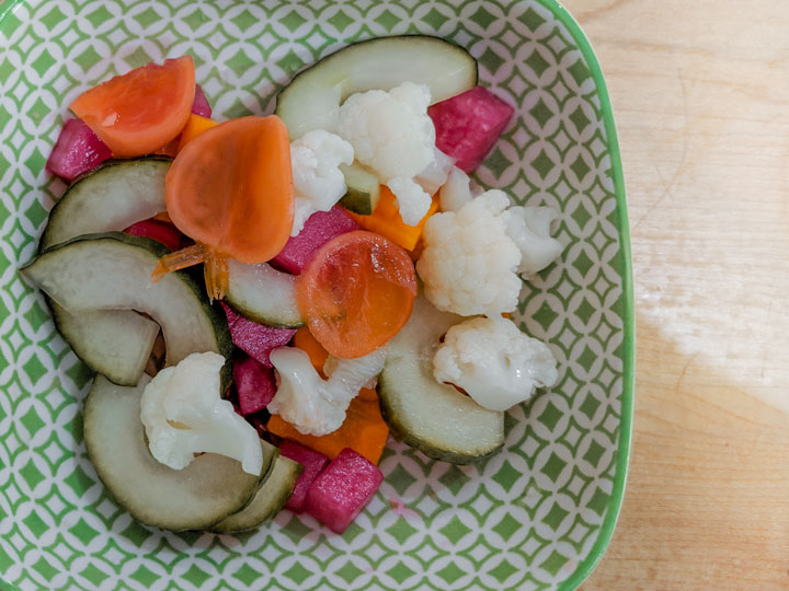 Japanese pickles (tsukemono) of cauliflower, carrot, and cucumber in green bowl.