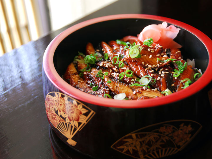 Red and black bowl filled with grilled unagi-no-kabayaki, a famous Japanese dish.