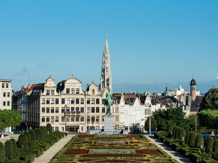 View of Brussels city from Mont Des Arts with garden and statue in foreground.