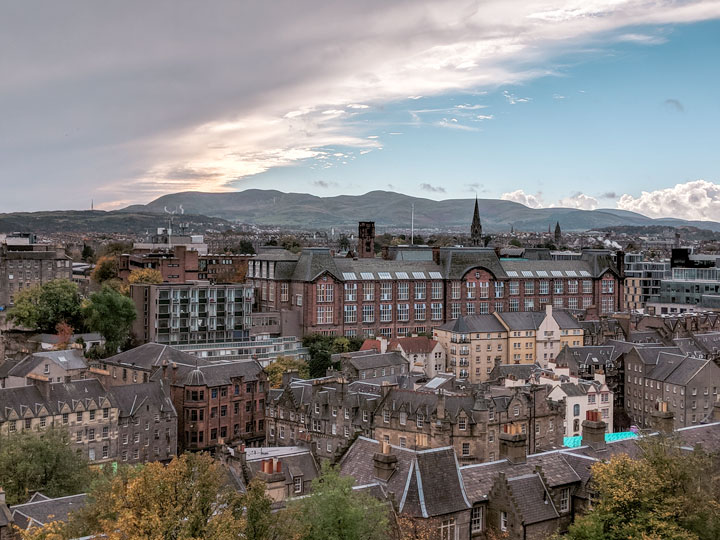 Sunset view over Edinburgh city, with hills in the distance.