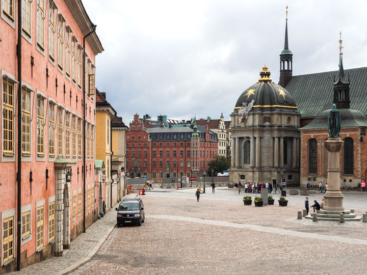 Stockholm pink and red buildings with domed church entrance in background.