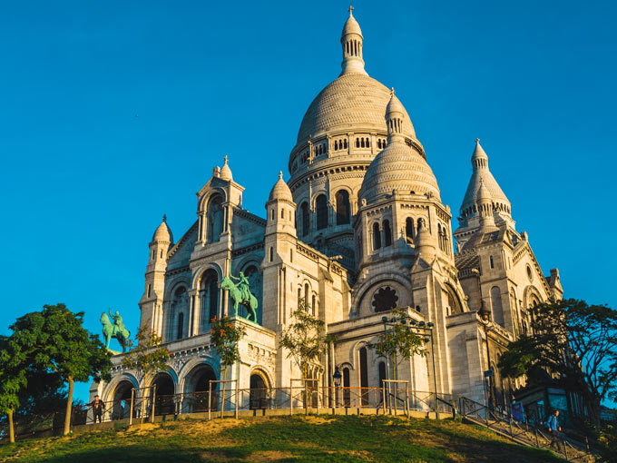 View of Sacre Coeur exterior against blue sky.