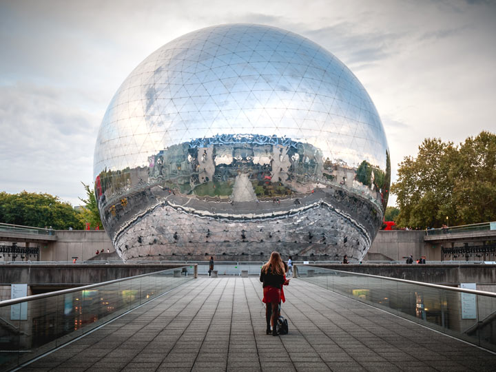 Woman looking at large reflective sphere in Paris Parc Villette.