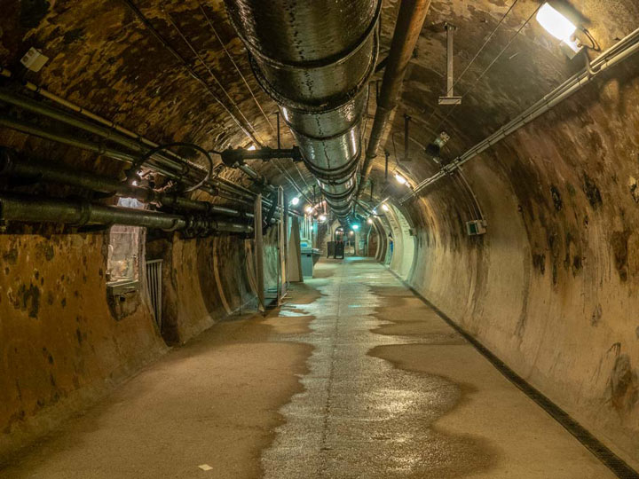 Interior of Paris Sewer Museum tunnel with wet floor and dim lights.