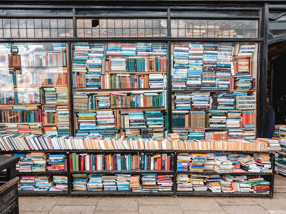 Exterior of secondhand bookshop with windows stacked full of used books.