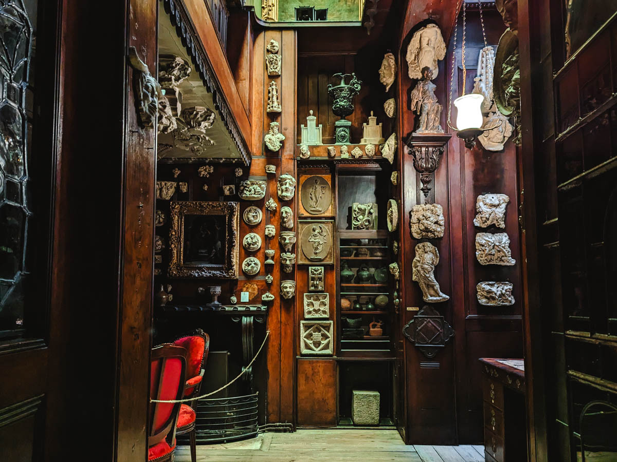 Interior room of John Soane Museum with numerous sculptures mounted on walls.