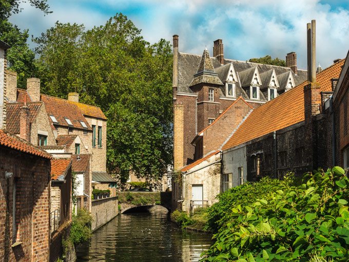 View of canal-side houses and trees in Bruges.