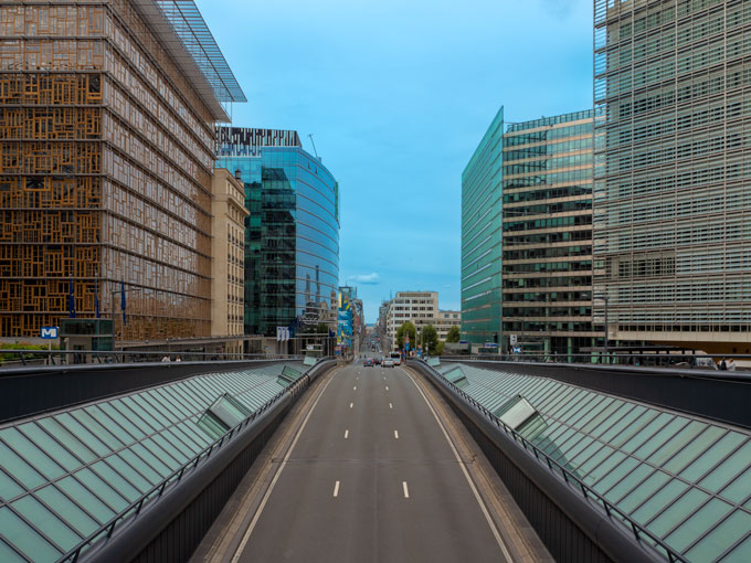 View down highway in Brussels with tall buildings on either side.