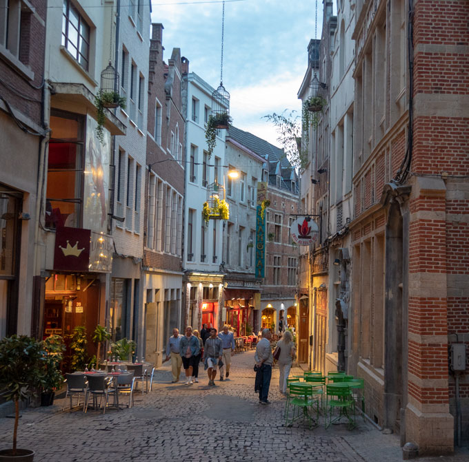 Brussels alley at night with people walking down cobbled street.