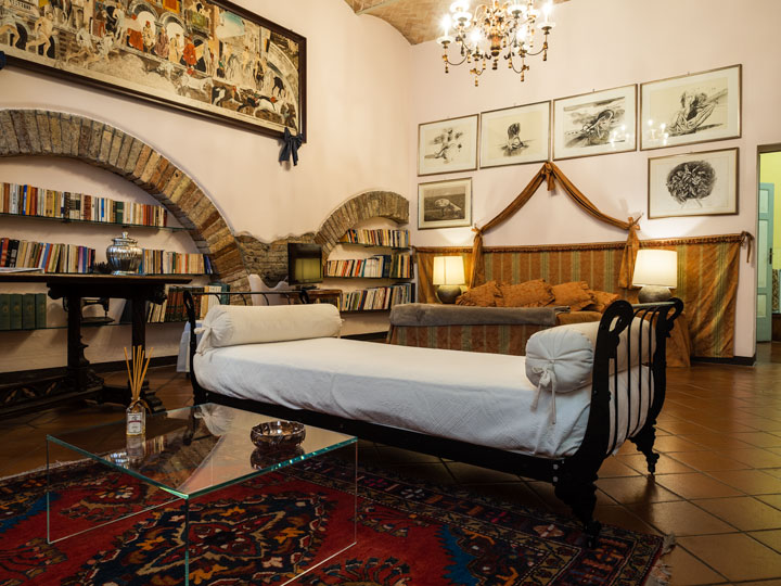 Casa Masoli room interior with lounge, bed, and bookshelves.