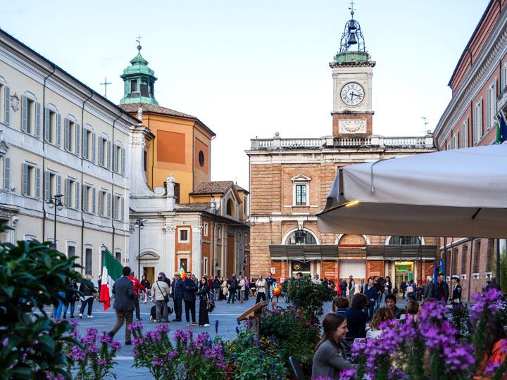 One day in Ravenna - busy town square with purple flowers and clock tower.