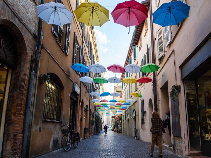 Ravenna Via Mentana umbrella street with bicycle and pedestrians.