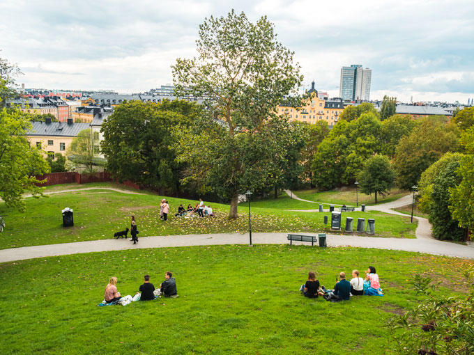 Groups of people sitting on grassy hill.