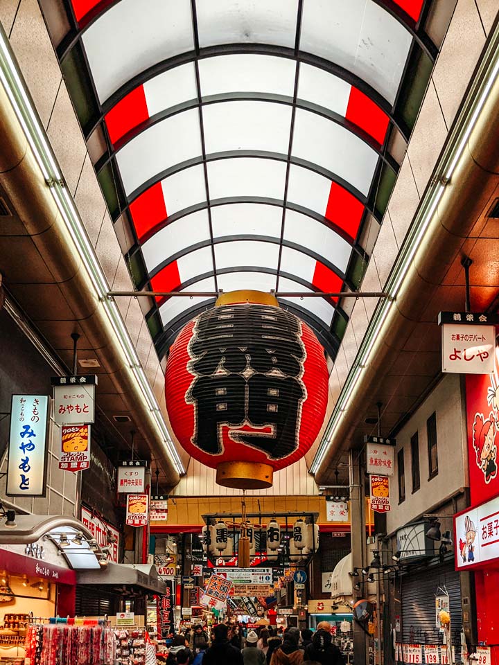 Large red lantern hanging from covered market ceiling