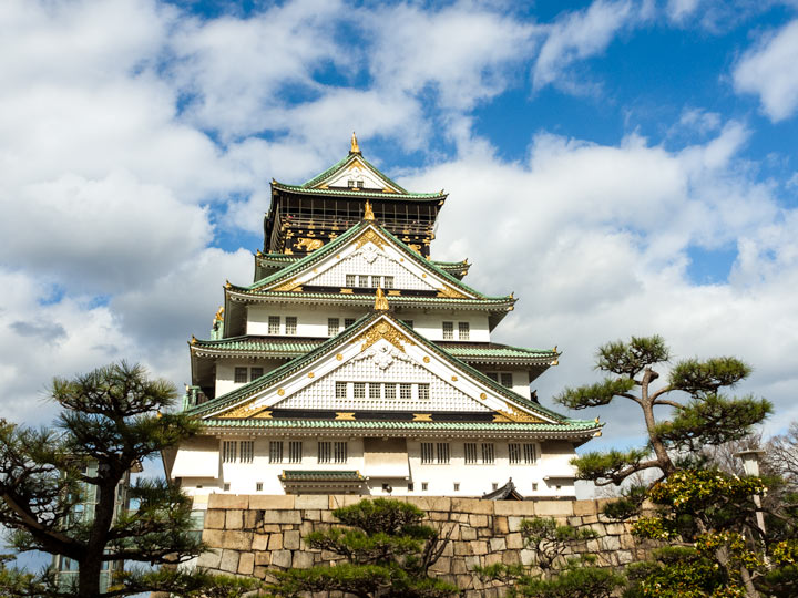 Osaka Castle with surrounding trees and partly cloudy sky