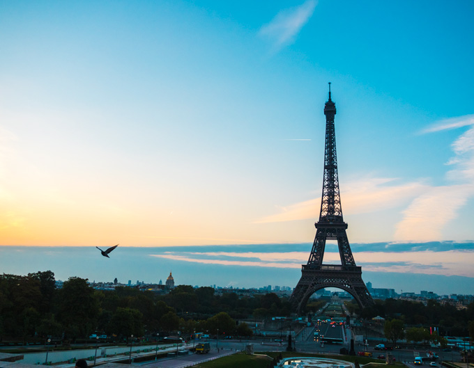 Eiffel Tower at sunrise against blue sky.