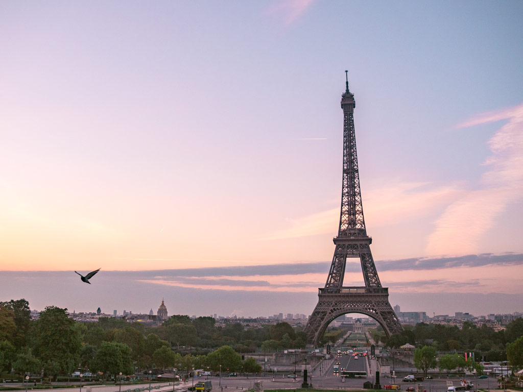 Paris Itinerary: 4 Days in the City of Light view of Eiffel Tower with purple and pink sunrise sky.