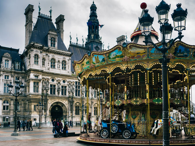 Hotel de Ville exterior with vintage carousel and lamp post in front.