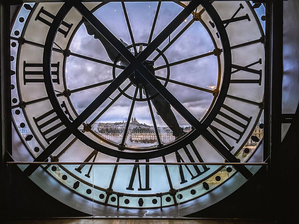 Musee d'Orsay clock face with view of city skyline.