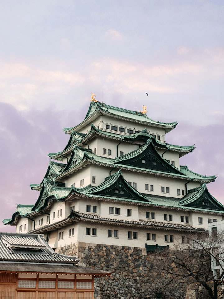 Nagoya Castle against purple sunset sky.