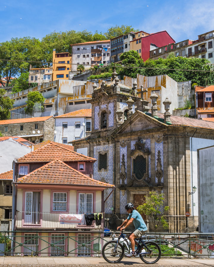 Cyclist riding in front of Porto Ribeira houses, part of Porto itinerary bike tour.