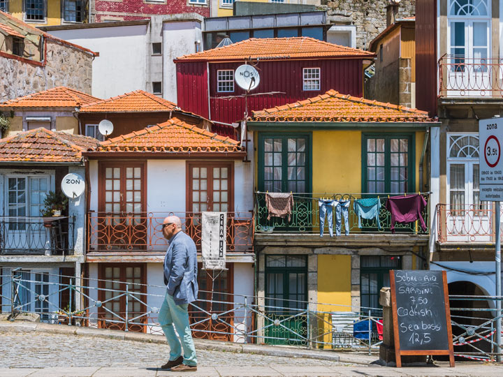 Man walking in front of colorful Porto Ribeira houses, a must see during 2 days in Porto.