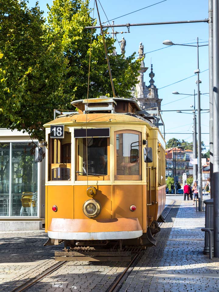 Yellow vintage tram in Porto running on tracks.