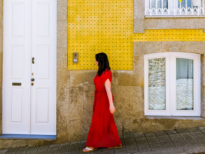 Girl in red dress in front of yellow tile wall in Foz do Douro Porto neighborhood.