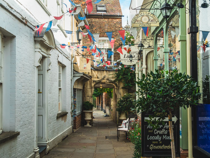 Alley in Gloucester with bunting flags and plants, part of UK road trip itinerary.