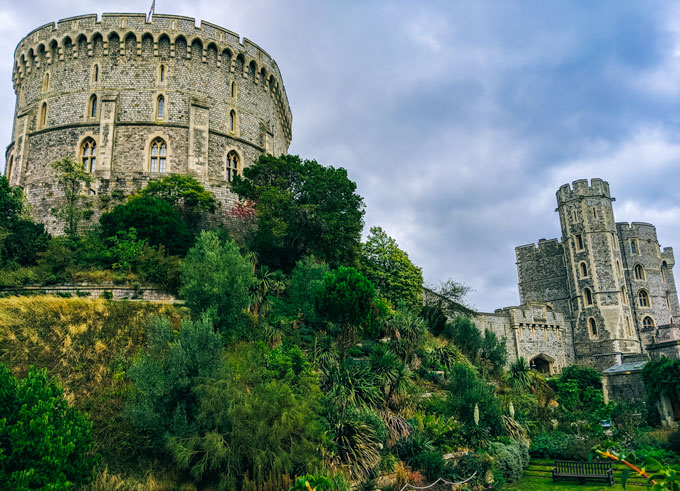 View of Windsor Castle UK exterior with foliage growing up hill.