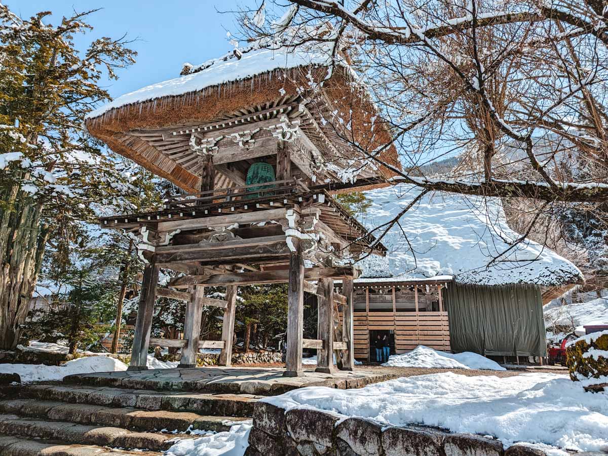 Myozenji bell tower made of wood and thatched roof with icicles hanging from top.