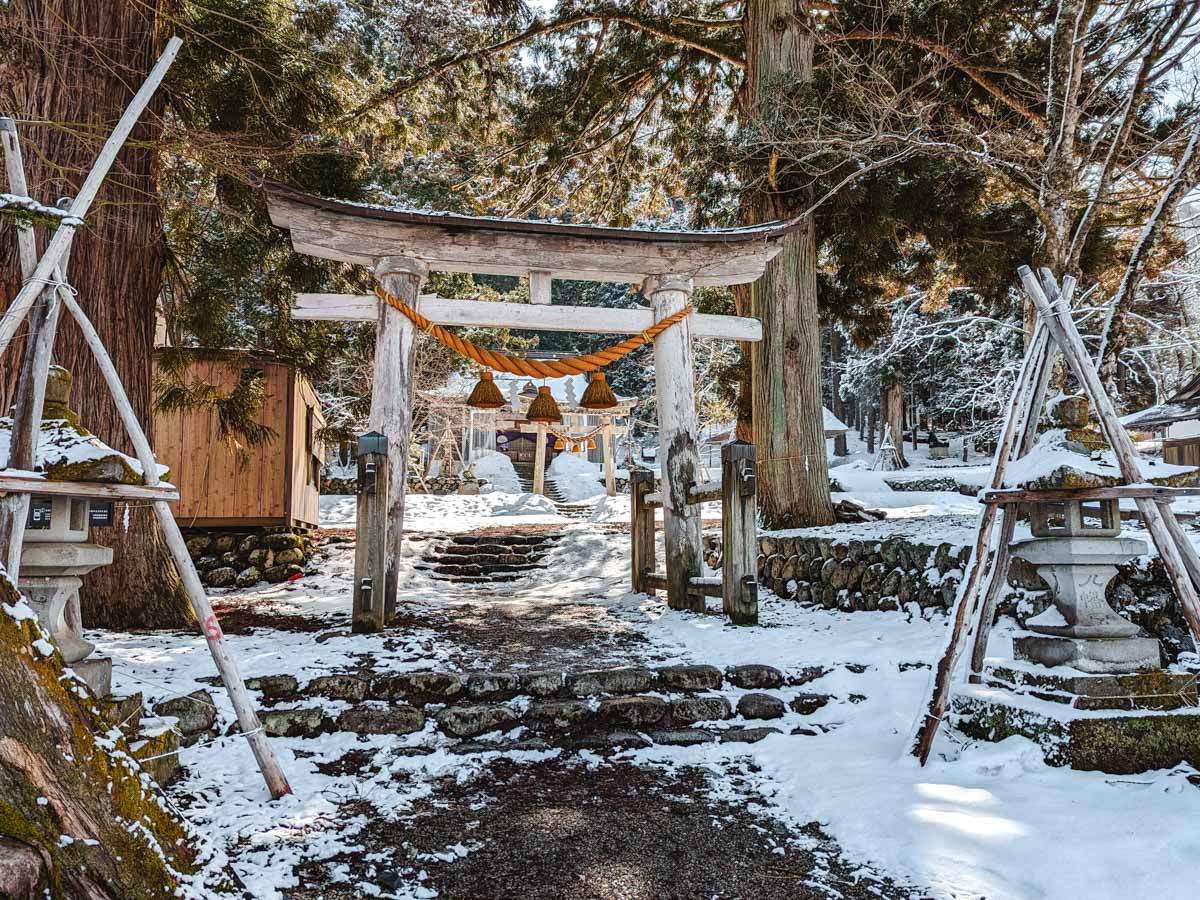 Wooden torii gates and stone lanterns along pathway leading to Myozenji shrine.