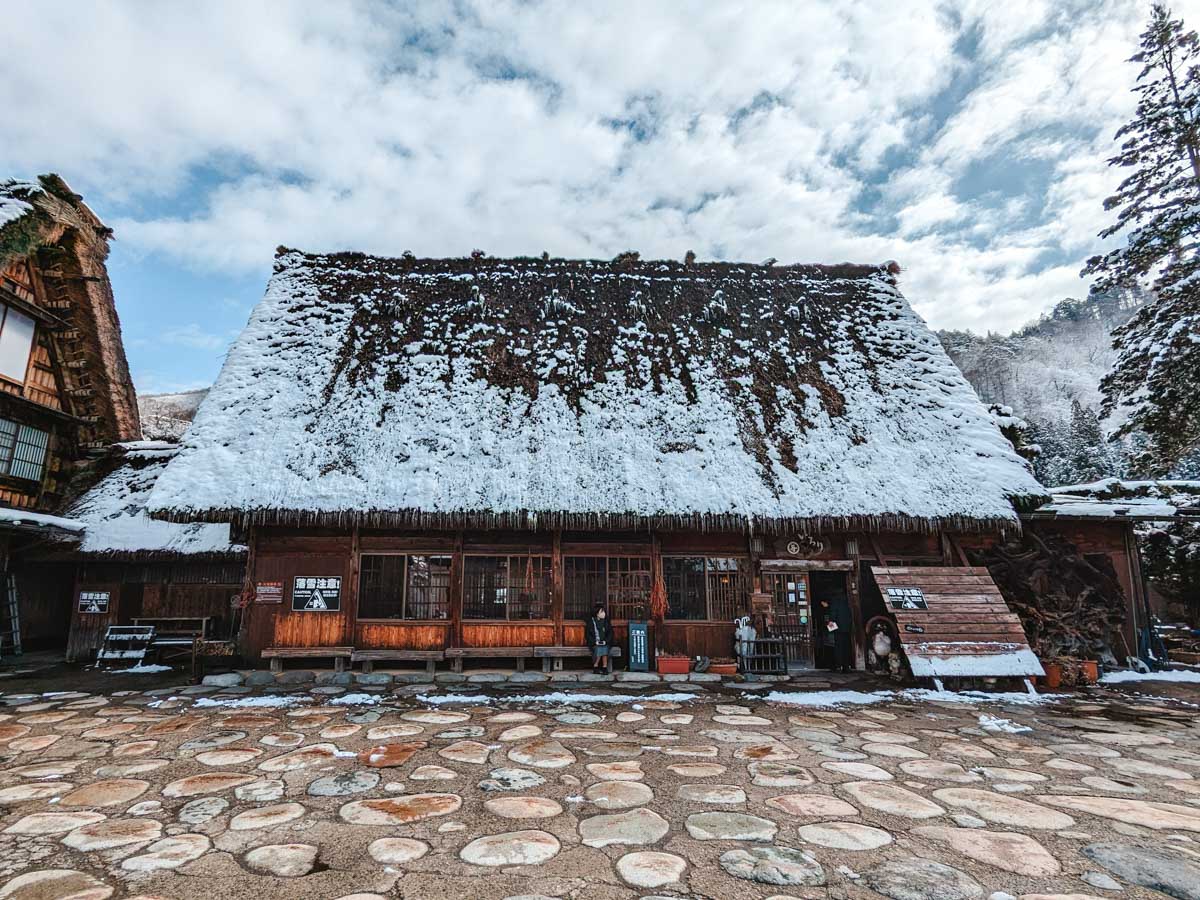 Large Gassho style cafe and souvenir shop with snowy roof.