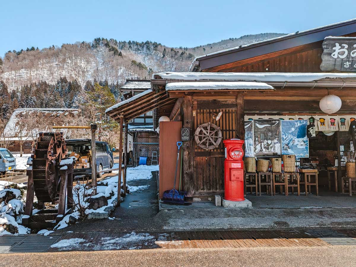 Facade of souvenir shop with water wheel and red postbox in Shirakawago.