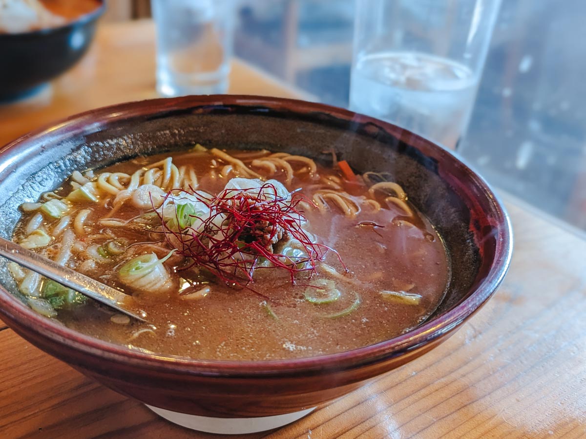 Close up of bowl of miso ramen on top of wooden table.