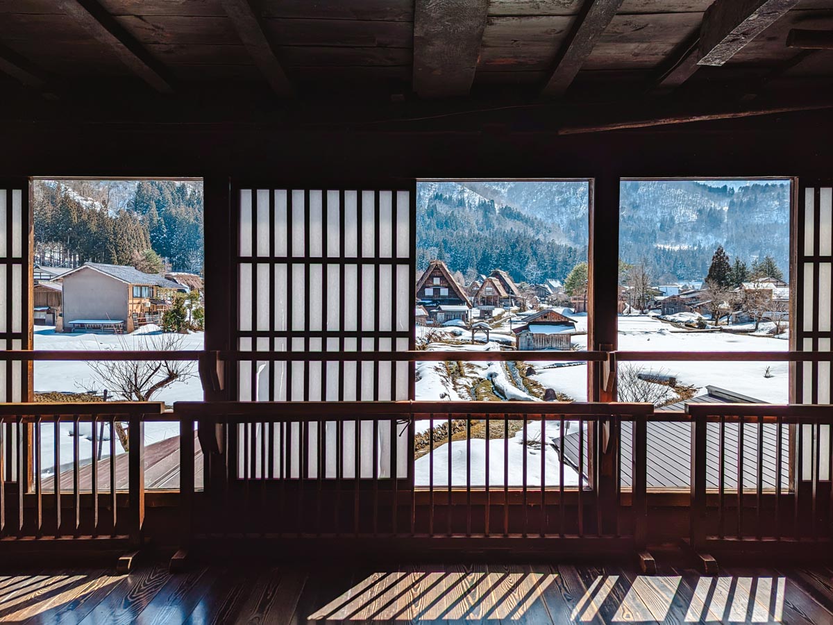 Wada House windows with shoji screens pulled open to reveal view of Shirakawago village.