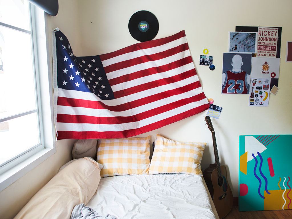 Small room with US flag, posters, guitar, bed and other things Americans miss living in the UK.