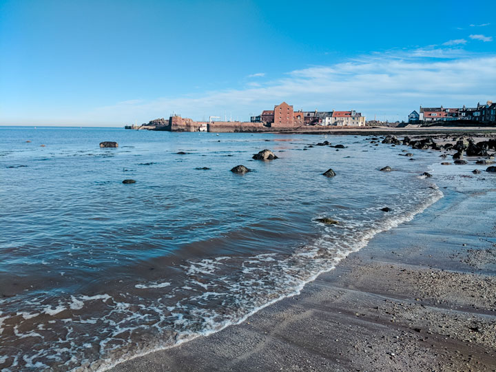 North Berwick Beach with wave coming in and village in background.