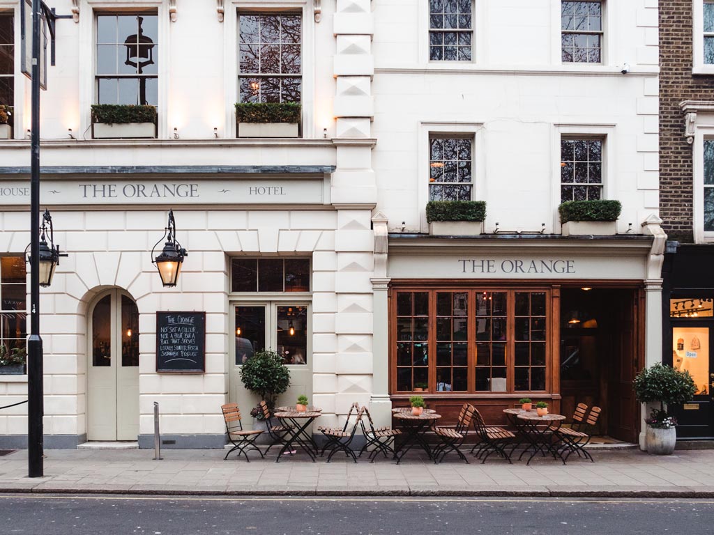 White stone exterior of hotel with outdoor cafe seating in London.