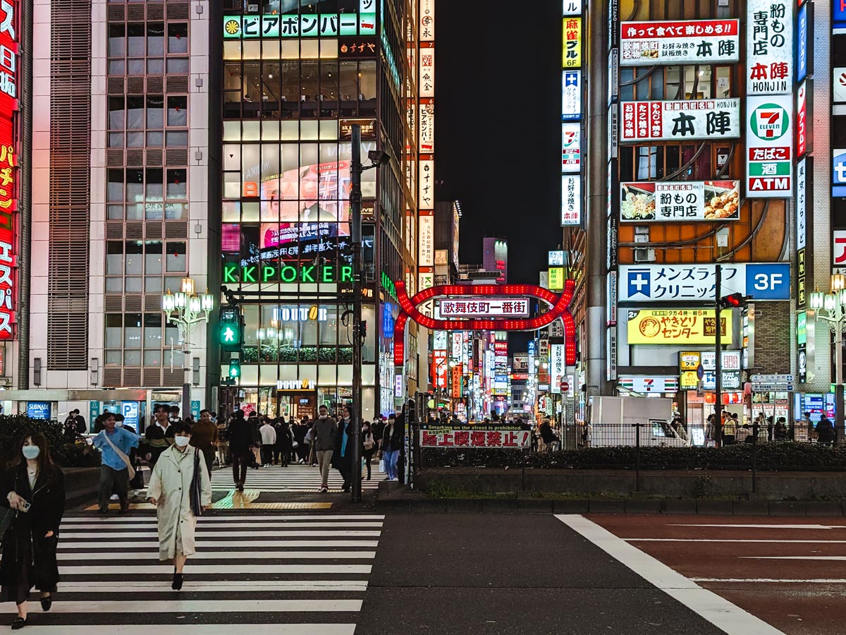 Street view of Shinjuku buildings and billboards at night among tourists doing 6 day Tokyo itinerary.