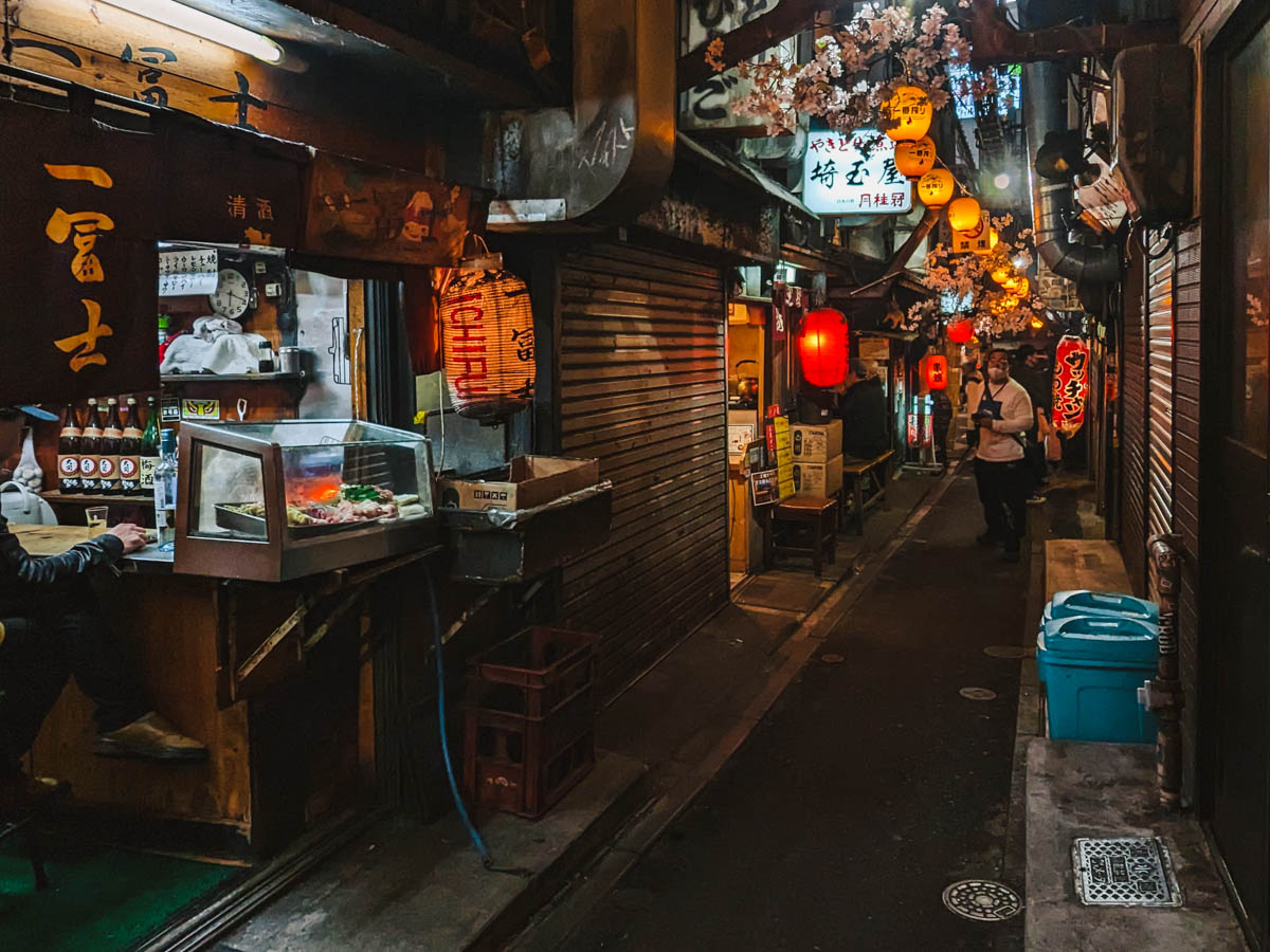 View down Omoide Yokocho alley at night with lanterns hanging above.