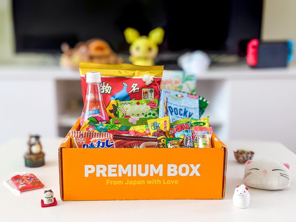 Orange TokyoTreat review box sitting open on white table, with snack packages sticking out.