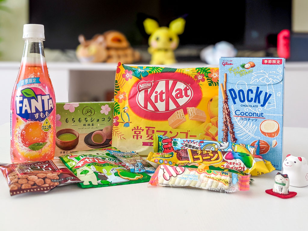 Arrangement of sweet Japanese snacks including Kit Kats, Pocky, and Fanta soda.