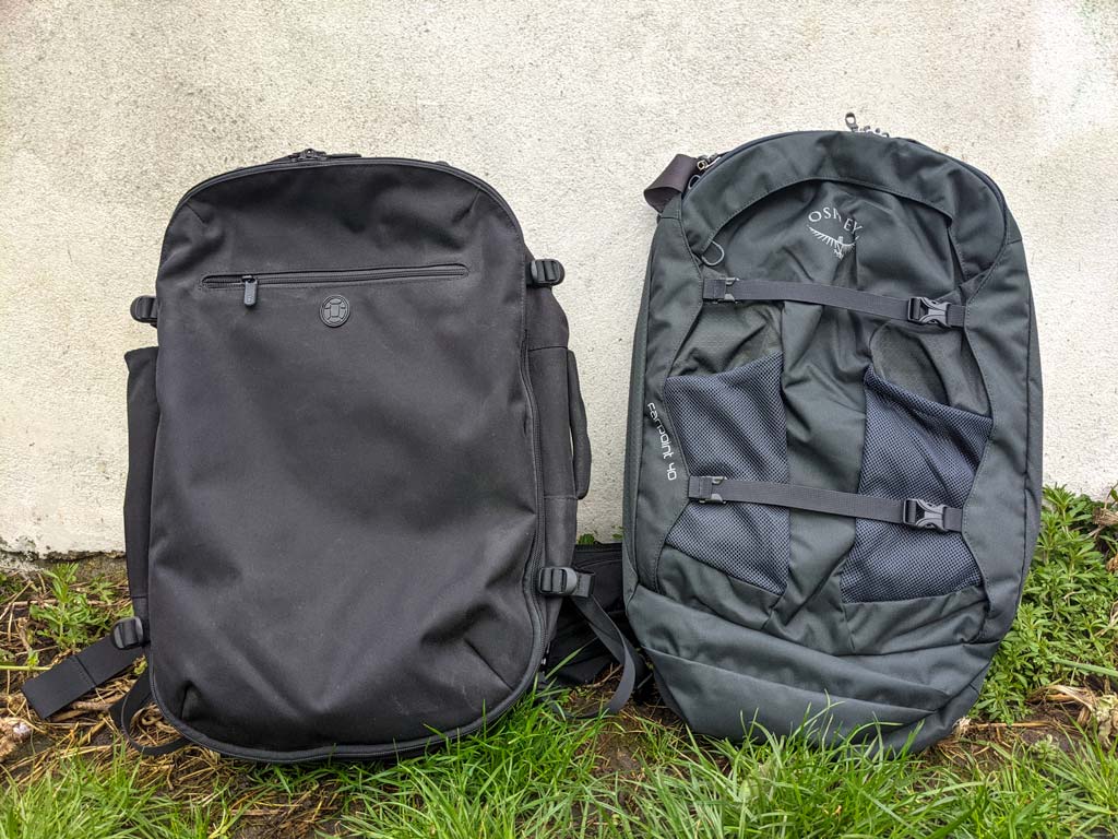 Side-by-side front view of black Tortuga Setout vs Osprey Farpoint backpacks on grass.