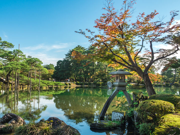 Kanazawa Kenrokuen garden pond with moss rocks and Japanese maple.