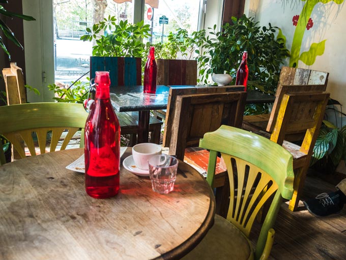 Interior of French breakfast cafe with wooden table and green chairs.