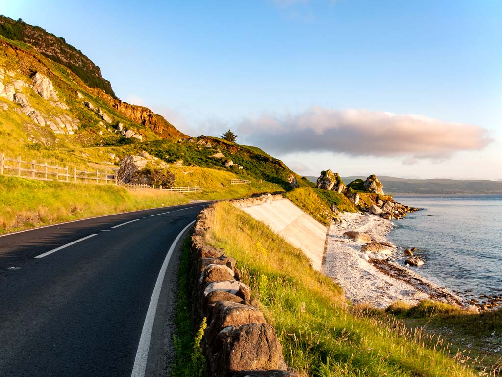 Antrim coast road with view of ocean at sunset.